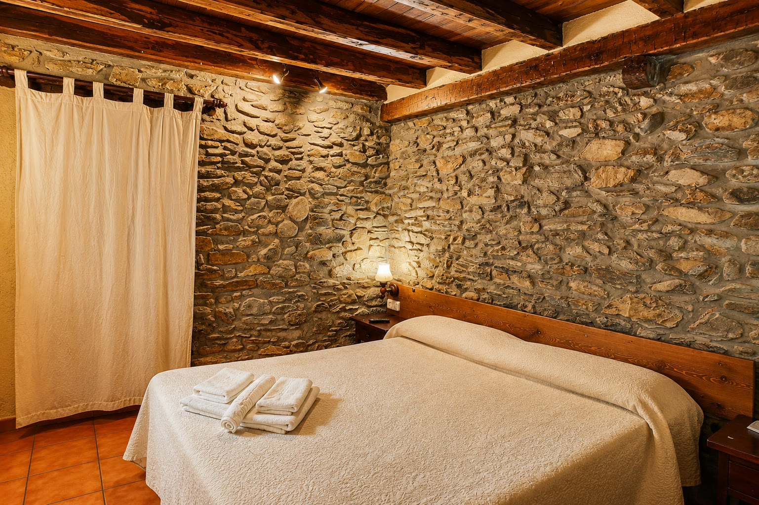 Habitació de l'Hostal Rusó amb parets de pedra i llum càlida